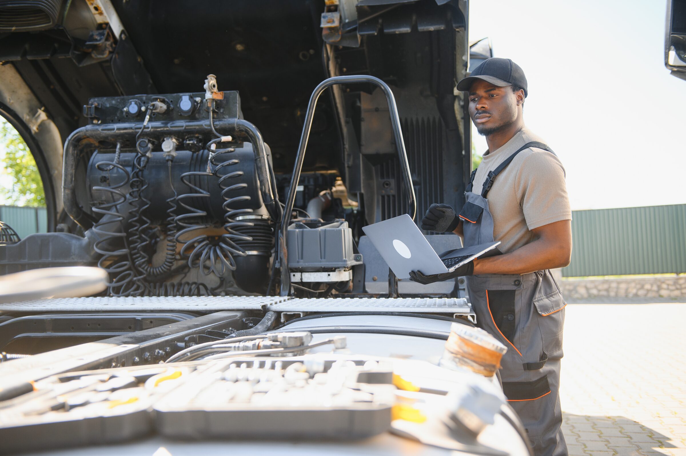 Mechanic diagnosing truck engine with laptop